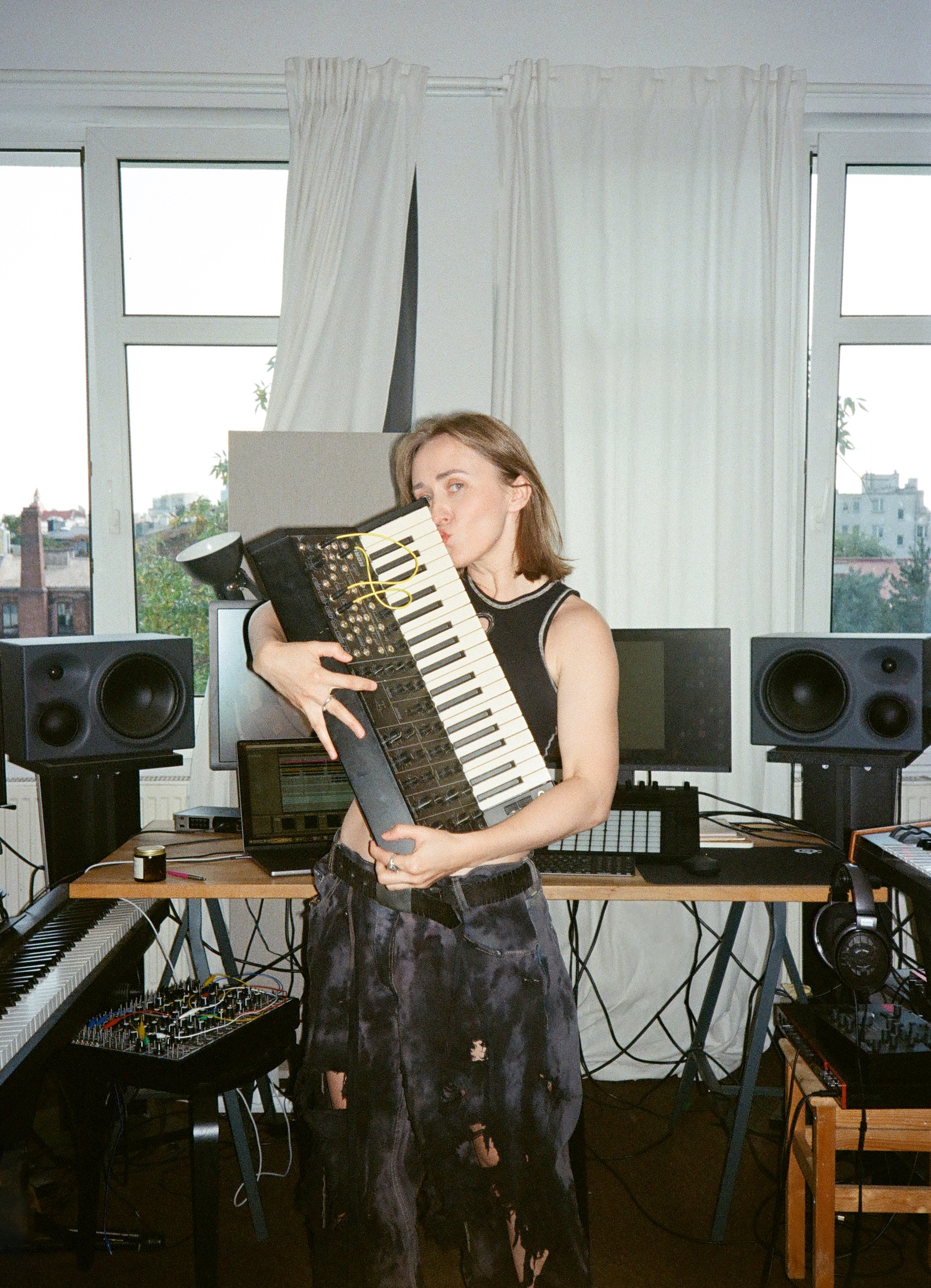 Wioleta Wnorowska in her studio holding a synthesizer